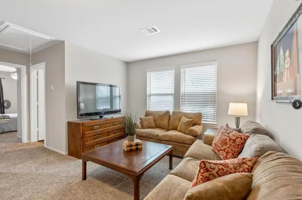 a living room with furniture a flat screen tv and a window