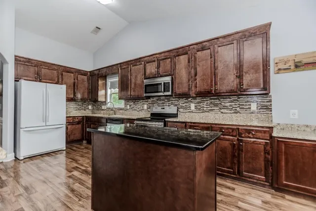 a kitchen with granite countertop wooden cabinets a refrigerator and a sink