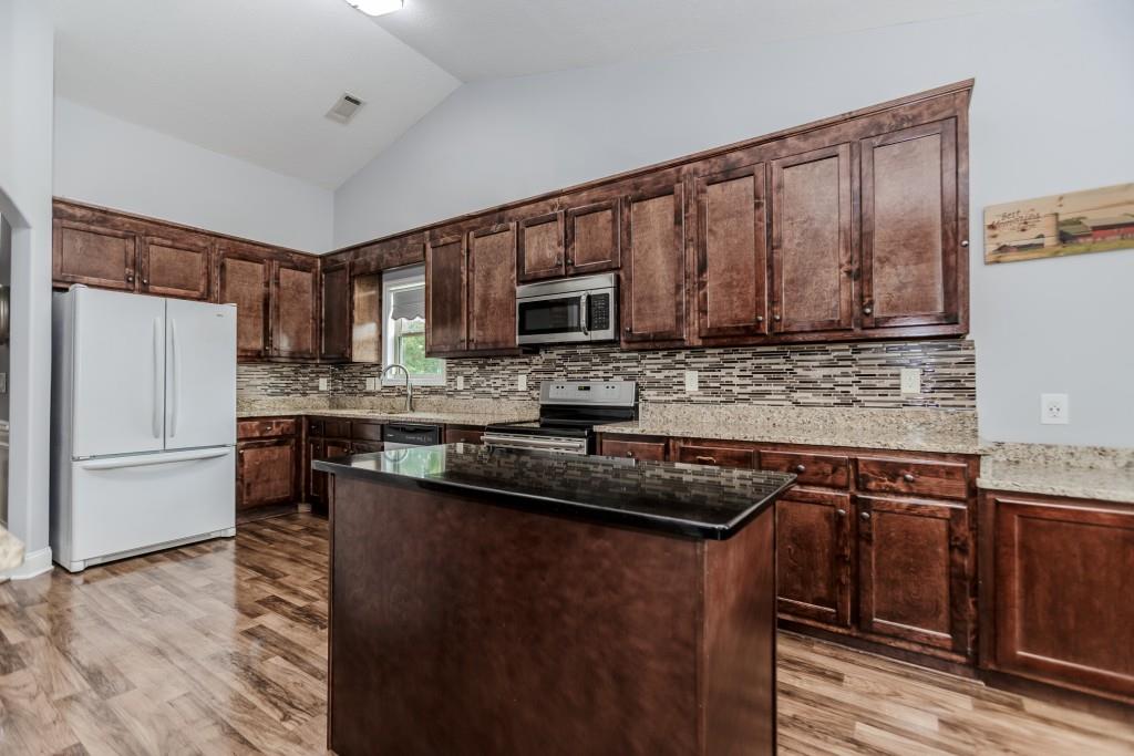 1411 Silvergate Way Winder, GA 30680 - Photo 15 of 38 a kitchen with granite countertop wooden cabinets a refrigerator and a sink