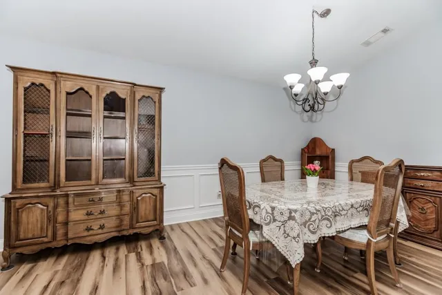 a dining room with furniture a chandelier and wooden floor