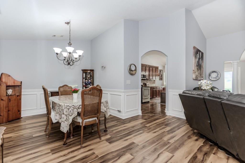 1411 Silvergate Way Winder, GA 30680 - Photo 20 of 38 a dining room with wooden floor a chandelier a wooden table and chairs