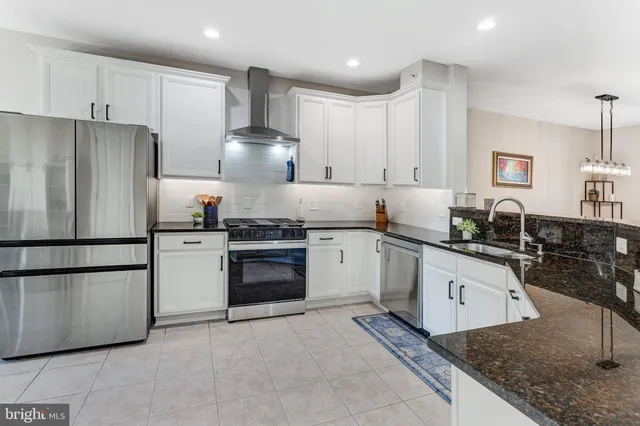 a kitchen with granite countertop a refrigerator stove top oven and sink
