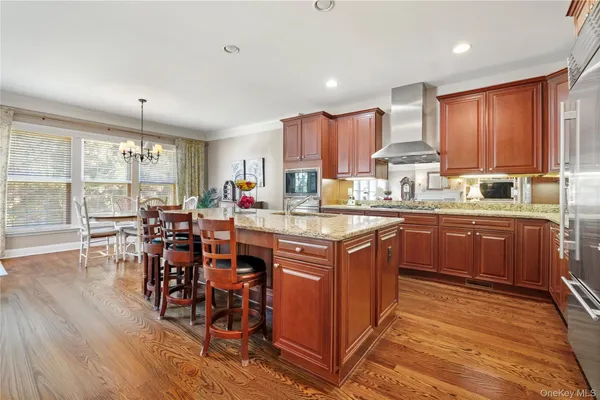 a kitchen with stainless steel appliances kitchen island granite countertop a table chairs and a refrigerator