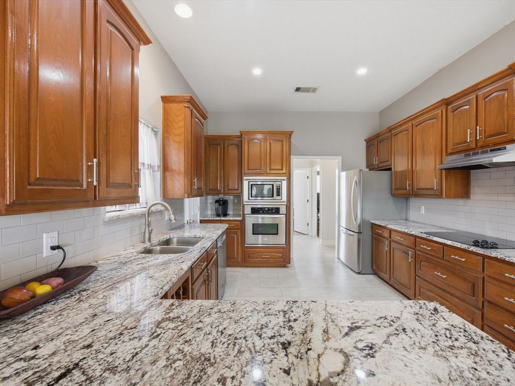 10106 Ravenswood Road Granbury, TX 76049 - Photo 5 of 39 a large kitchen with stainless steel appliances a stove a sink and a refrigerator