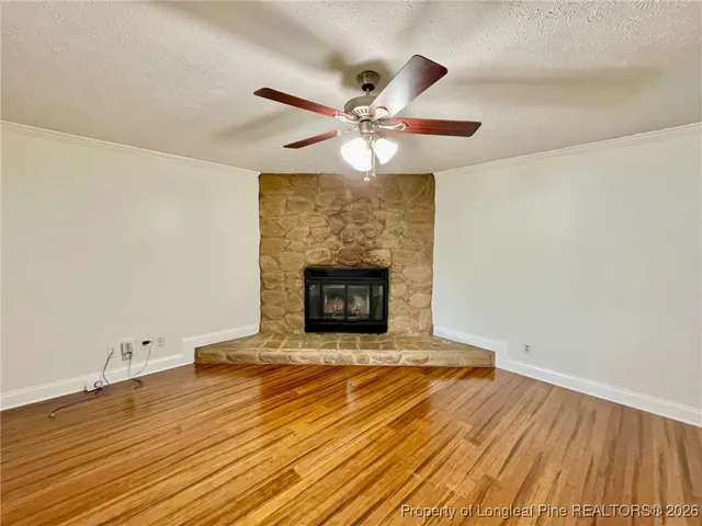 a view of an empty room with wooden floor and a fireplace