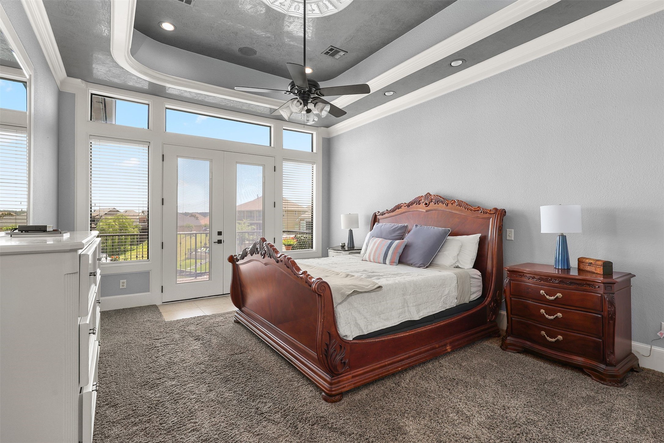 10896 Decatur Street Willis, TX 77318 - Photo 32 of 50 Discover a spacious, elegantly designed bedroom featuring a luxurious wooden bed, plush carpeting, and a ceiling fan, with large windows and French doors providing abundant natural light and seamless access to a balcony with breathtaking views.
