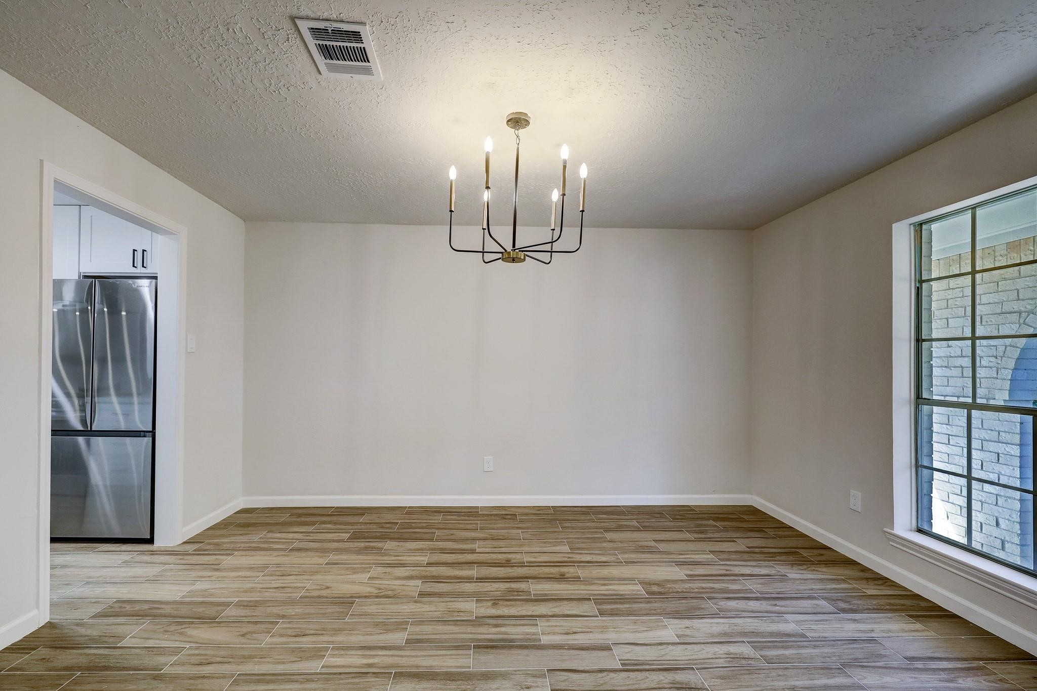 9723 Galston Lane Spring, TX 77379 - Photo 4 of 24 This dining space is brightened by an oversized window and anchored by a contemporary chandelier. The neutral color palette and warm wood-look floors enhance the atmosphere. Direct access to the kitchen makes hosting seamless.