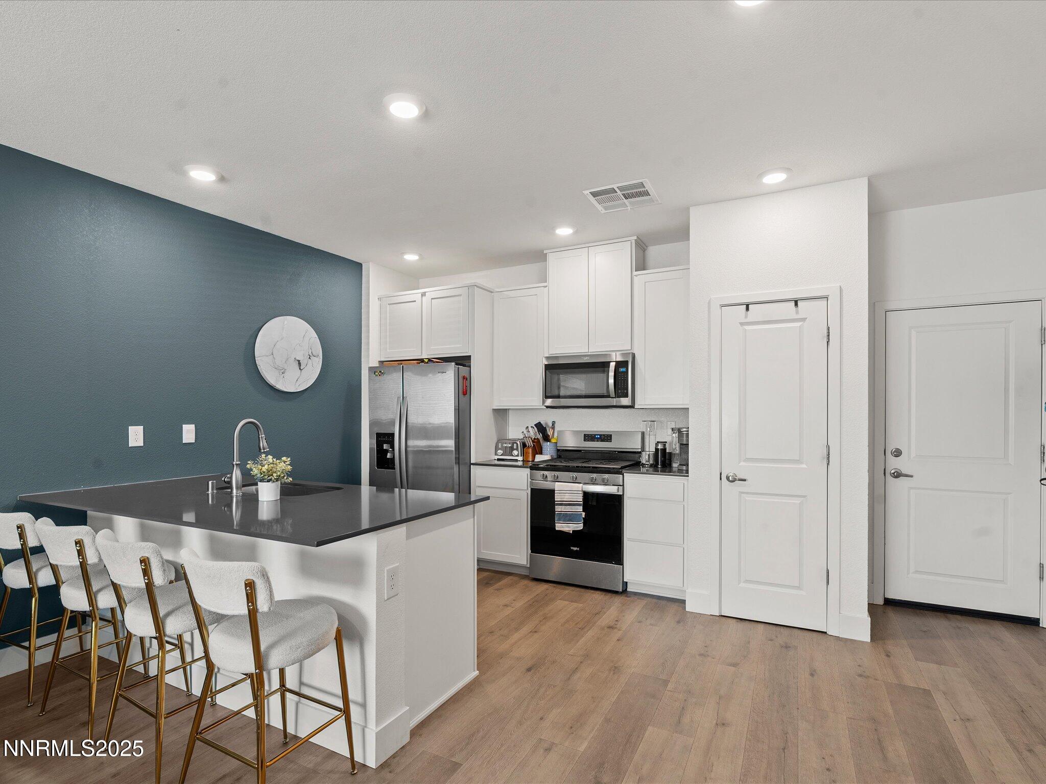4232 Fawnridge Place Reno, NV 89523 - Photo 5 of 39 a kitchen with stainless steel appliances granite countertop a stove a sink a refrigerator and white cabinets with wooden floor