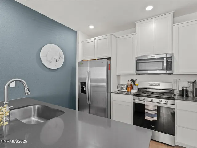 a kitchen with granite countertop a sink stainless steel appliances and cabinets