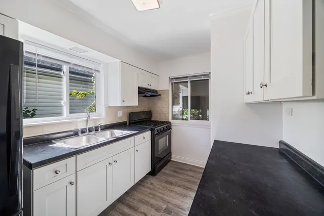 a kitchen with granite countertop white cabinets and a sink