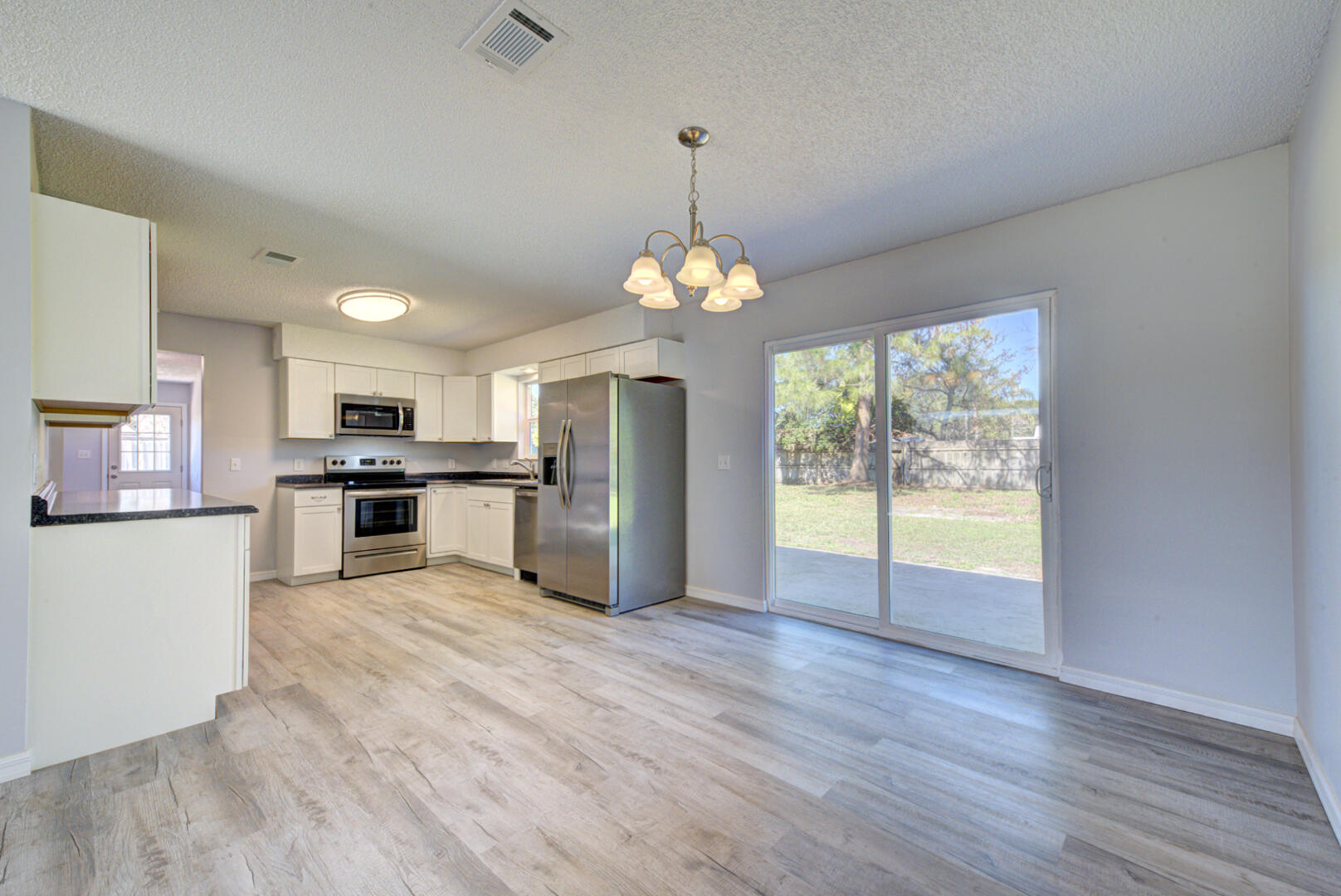 5356 Jamaica Road Cocoa, FL 32927 - Photo 13 of 41 a kitchen with stainless steel appliances granite countertop a refrigerator a oven a sink dishwasher and white cabinets with wooden floor