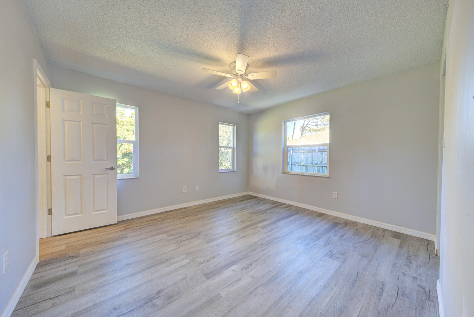 5356 Jamaica Road Cocoa, FL 32927 - Photo 23 of 41 an empty room with wooden floor chandelier fan and windows