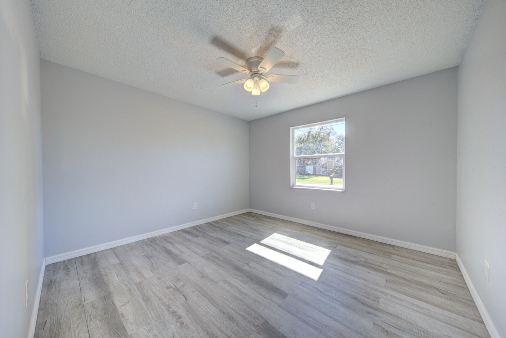 5356 Jamaica Road Cocoa, FL 32927 - Photo 32 of 41 an empty room with wooden floor a ceiling fan and window
