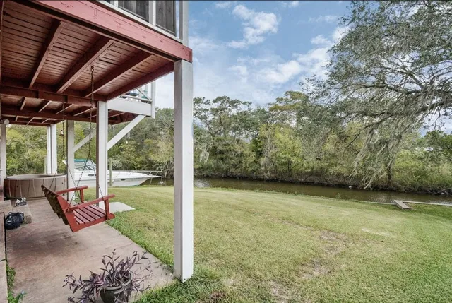 a view of a backyard with table and chairs under an umbrella with a large tree