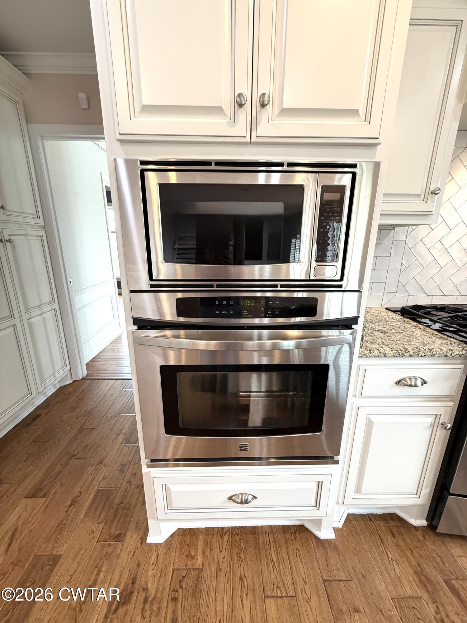2787 Meacham Road Dyersburg, TN 38024 - Photo 22 of 45 a stove top oven sitting inside of a kitchen with stainless steel appliances wooden floor and cabinets