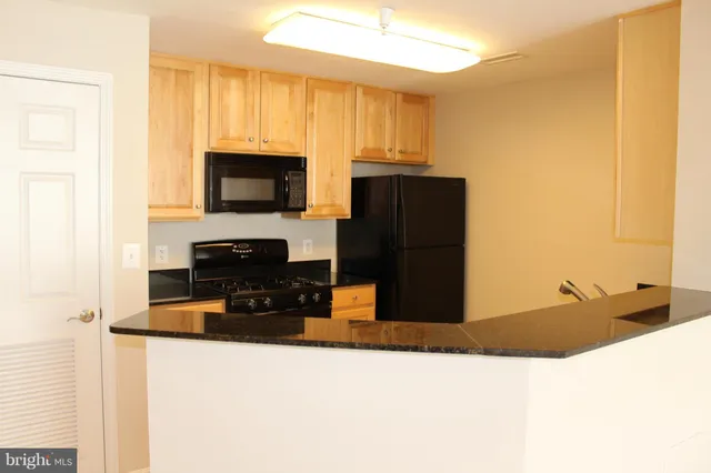 a kitchen with stainless steel appliances kitchen island granite countertop a refrigerator oven a sink with granite countertops and cabinets