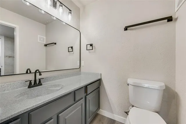 a bathroom with a granite countertop sink toilet and a mirror