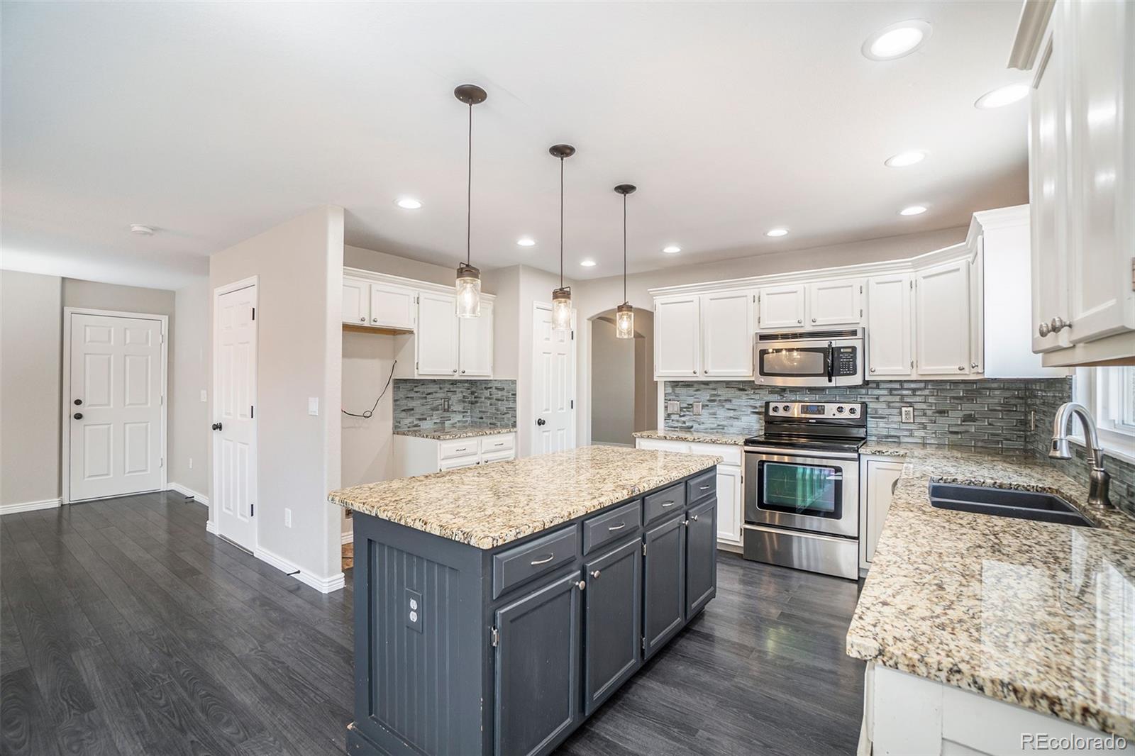 6000 South Summer Ridge Way Castle Rock, CO 80109 - Photo 4 of 19 a large kitchen with stainless steel appliances kitchen island granite countertop a stove a sink dishwasher and a refrigerator with wooden floor