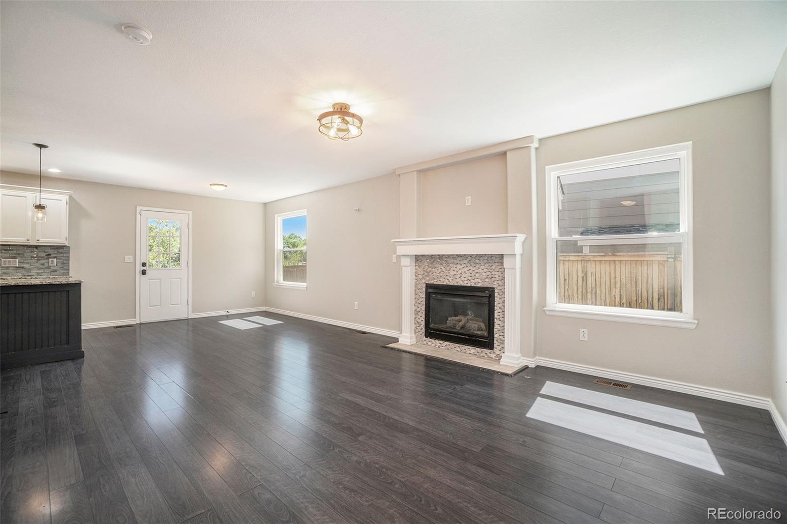 6000 South Summer Ridge Way Castle Rock, CO 80109 - Photo 5 of 19 an empty room with windows a fireplace and wooden floor