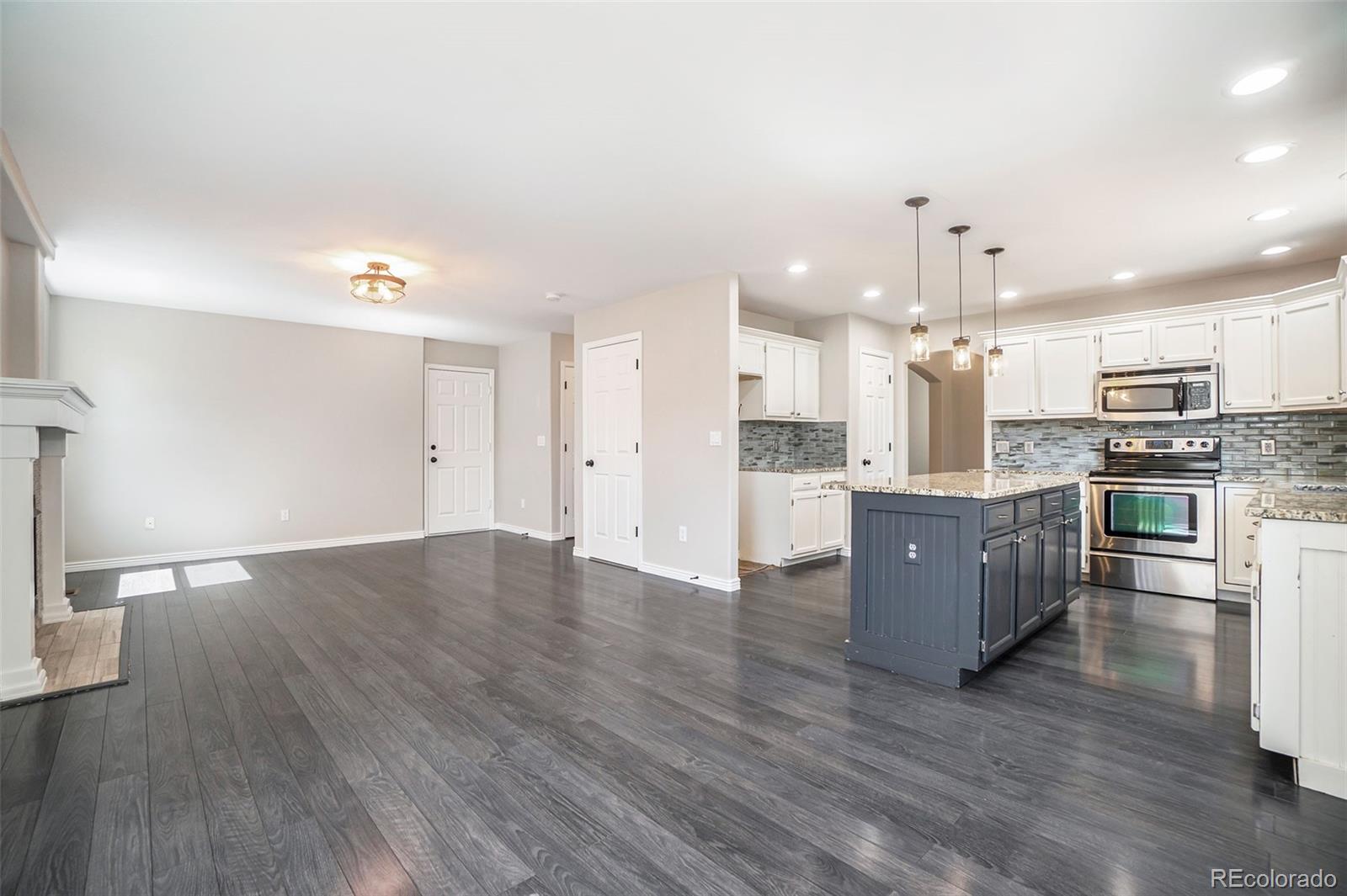 6000 South Summer Ridge Way Castle Rock, CO 80109 - Photo 9 of 19 a large kitchen with stainless steel appliances kitchen island granite countertop a large counter top and wooden floors