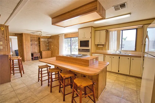 a dining hall with stainless steel appliances kitchen island granite countertop a table chairs and a refrigerator