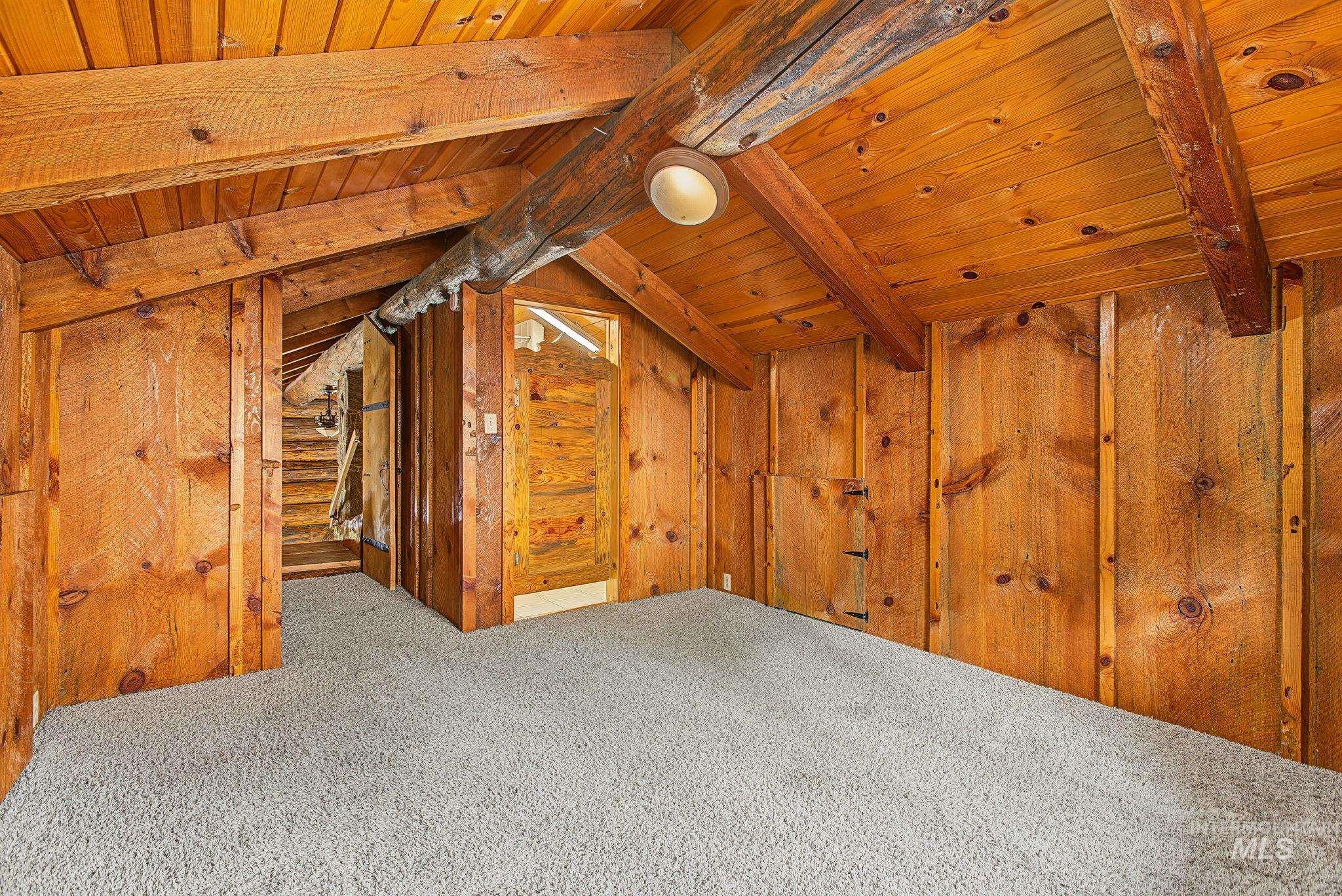 2926 Wells Bench Road Orofino, ID 83544 - Photo 32 of 48 Vaulted wood-paneled ceiling, exposed wood beams, wall-mounted light fixture, light gray carpeting, and natural wood wall panels