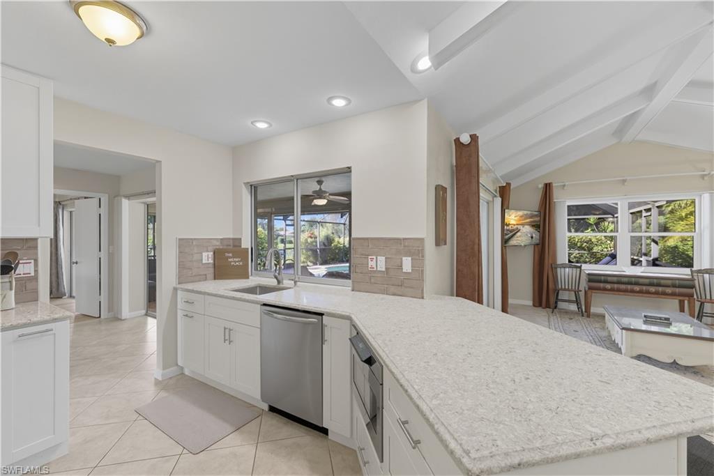 2261 Kings Lake Boulevard Naples, FL 34112 - Photo 11 of 43 a large white kitchen with a sink and dishwasher with a large kitchen island
