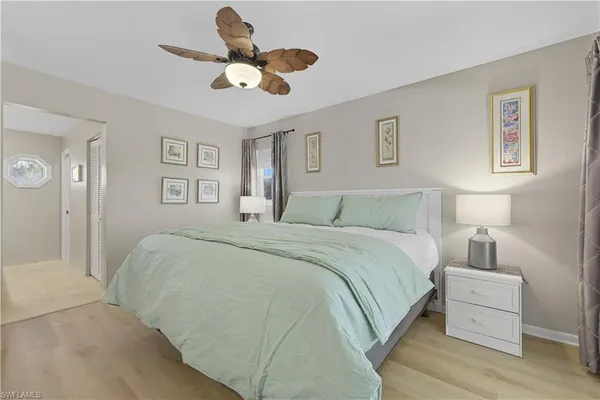 a bedroom with a bed chandelier painting on the wall and a large window