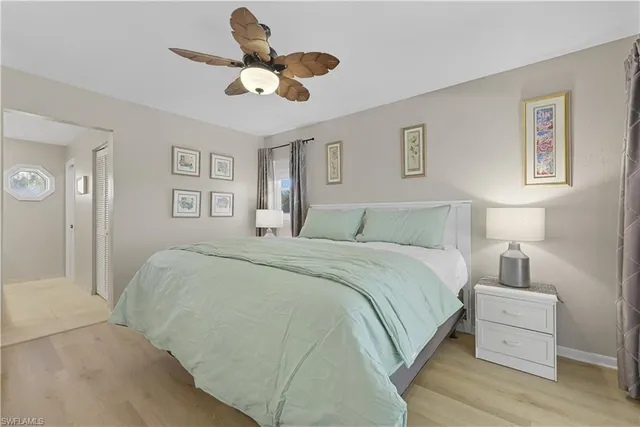 a bedroom with a bed chandelier painting on the wall and a large window