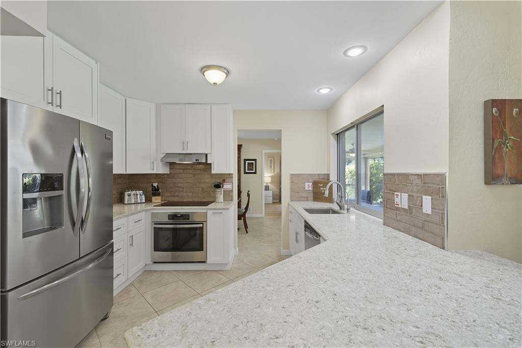 2261 Kings Lake Boulevard Naples, FL 34112 - Photo 10 of 43 a kitchen with refrigerator a stove and cabinets