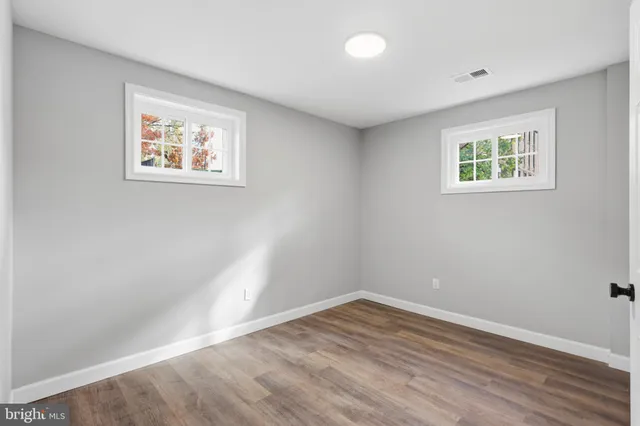 a view of an empty room with window and wooden floor