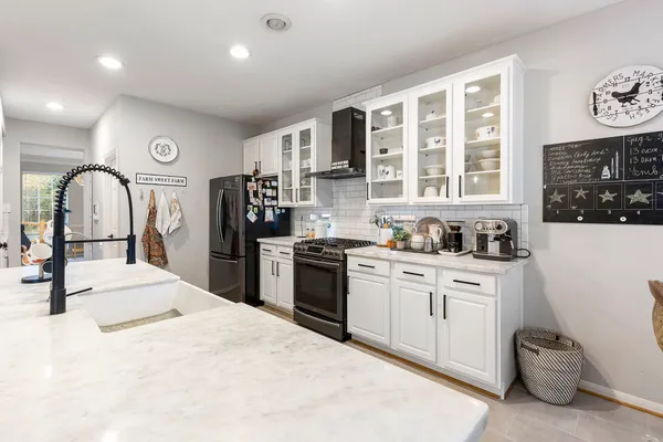a kitchen with stainless steel appliances granite countertop a stove top oven a sink a dining table and chairs