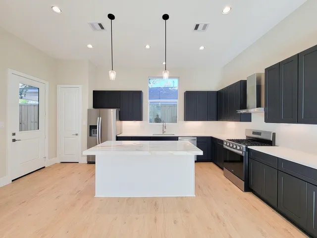 a large kitchen with stainless steel appliances granite countertop a stove a refrigerator a sink dishwasher and a wooden cabinets