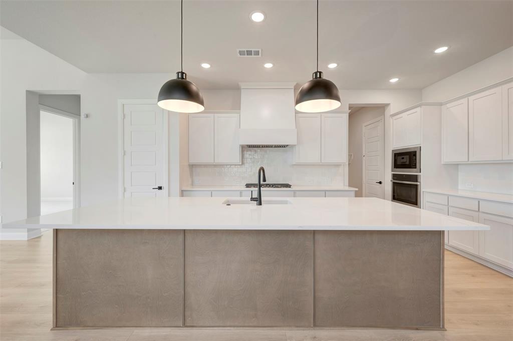 3575 Redbud Flower Trail Venus, TX 76084 - Photo 14 of 36 Kitchen featuring light wood-type flooring, a large island with sink, white cabinets, and stainless steel appliances