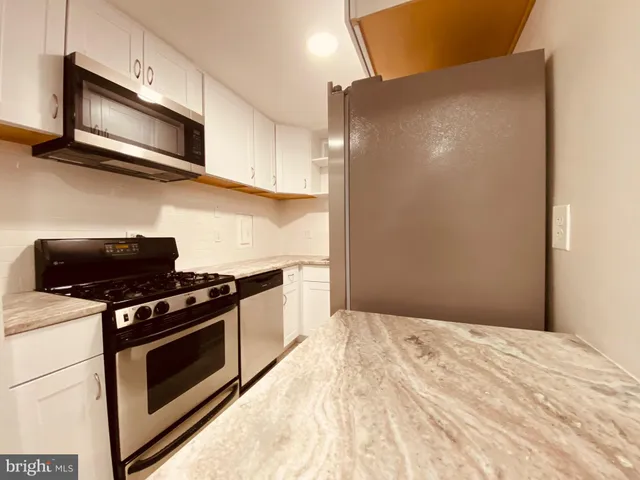 a kitchen with stainless steel appliances white cabinets and a stove top oven
