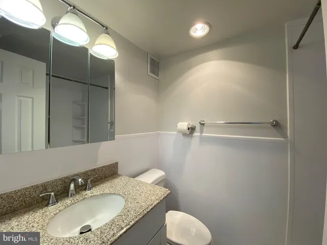 a bathroom with a granite countertop sink toilet and a mirror