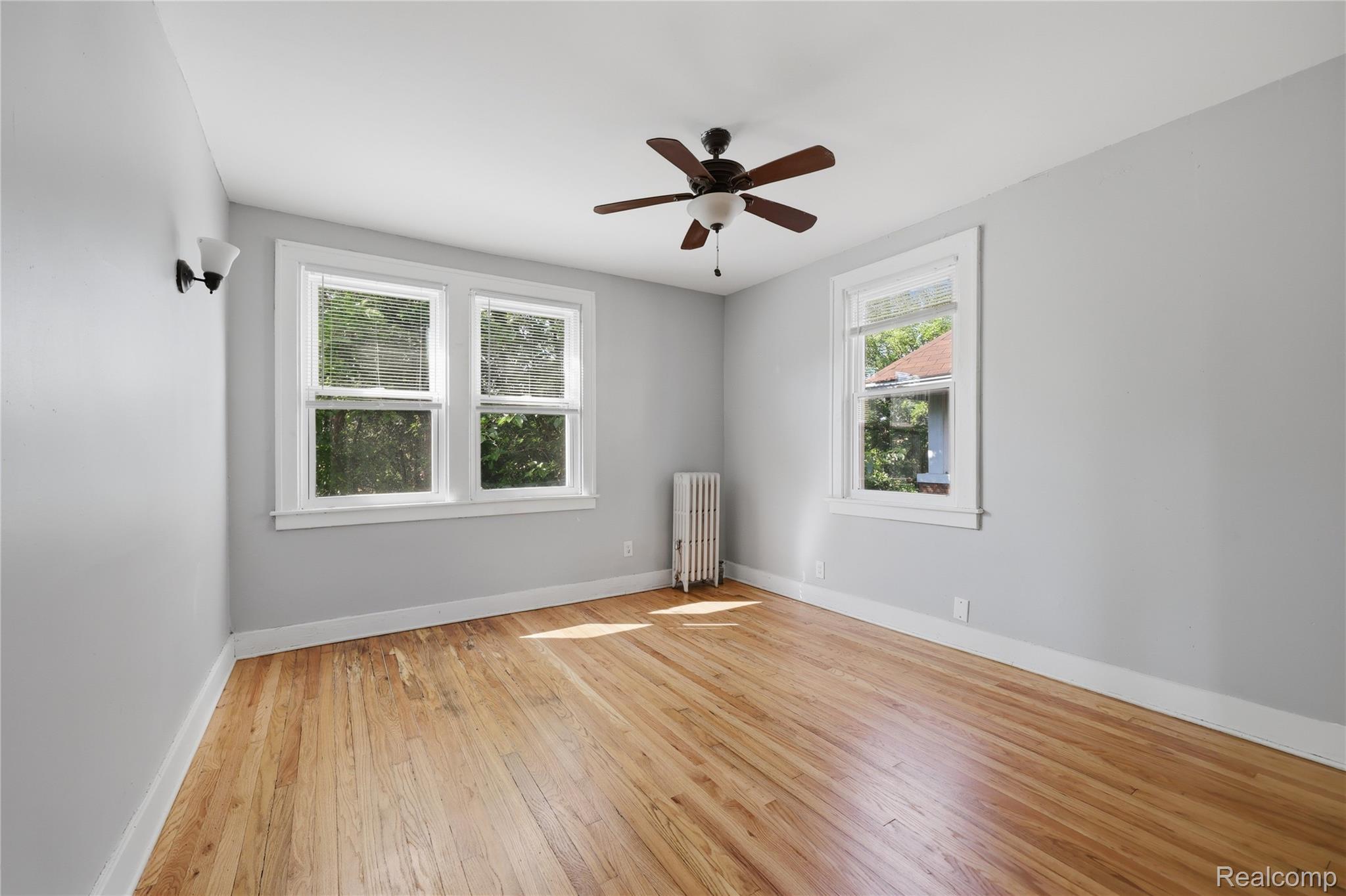 1945 Atkinson Street Detroit, MI 48206 - Photo 31 of 49 Wood-finish flooring throughout, featuring a ceiling fan with integrated lighting, multiple windows, white trim, and a wall-mounted sconce