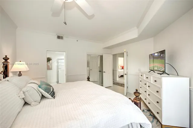 a bedroom with a bed and a flat tv screen on dresser