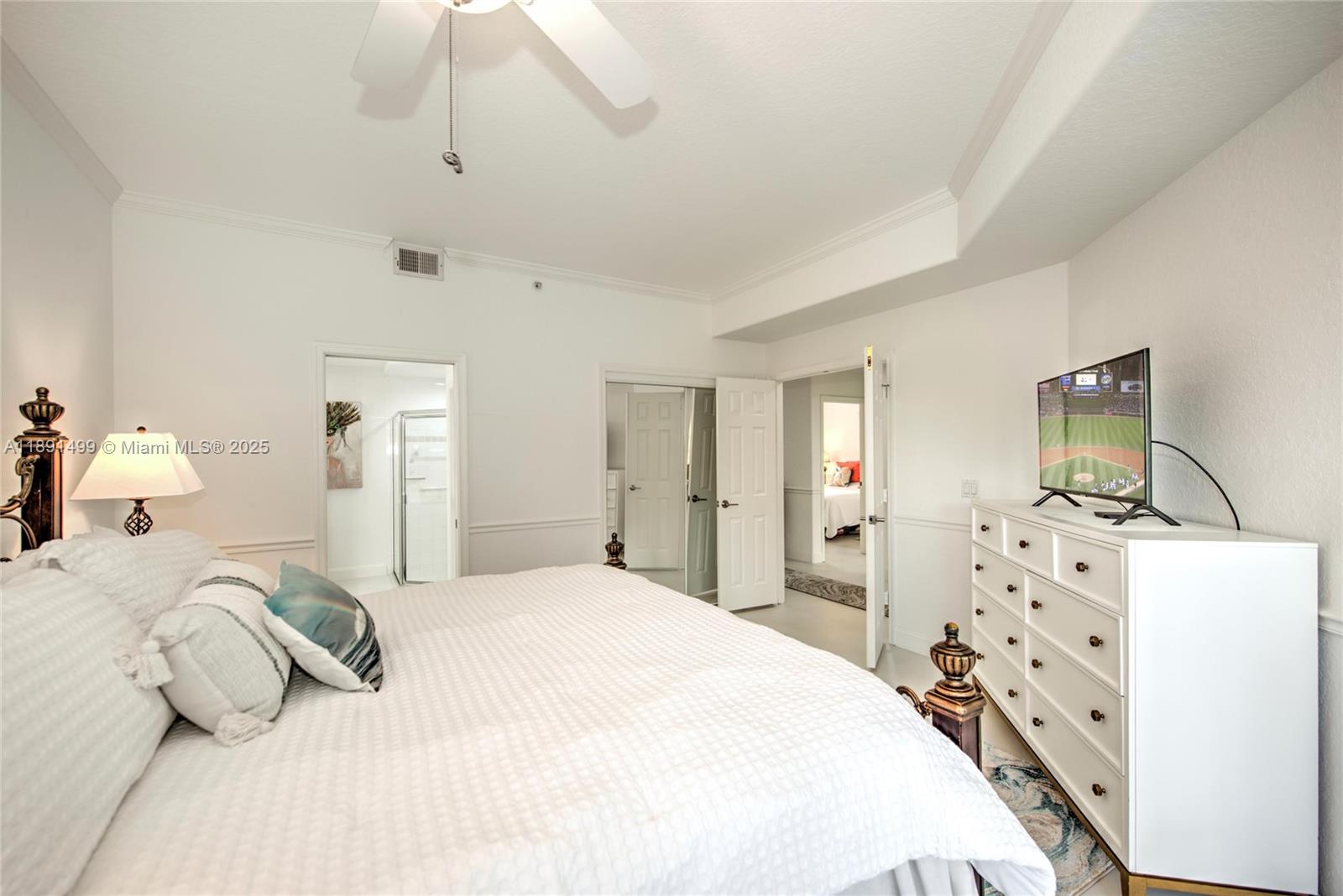 8385 Whisper Trace Way, Unit 104 Naples, FL 34114 - Photo 9 of 18 a bedroom with a bed and a flat tv screen on dresser