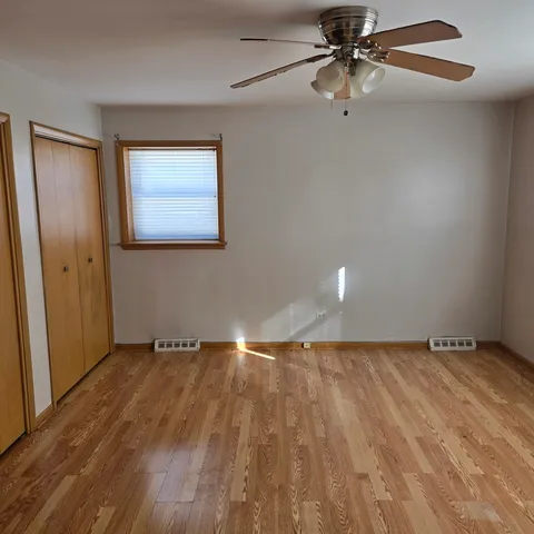 an empty room with wooden floor closet and fan