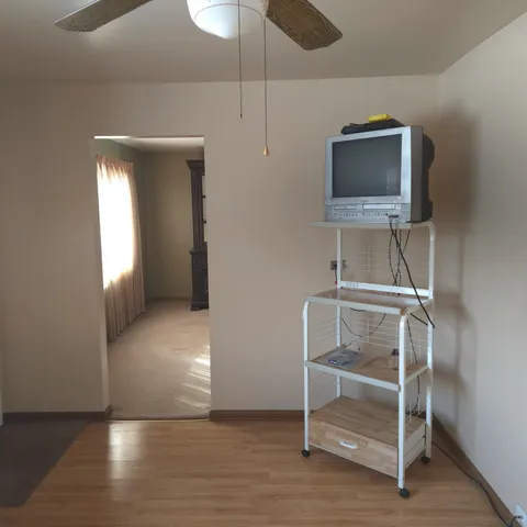 a view of an empty room with wooden floor and a cabinet