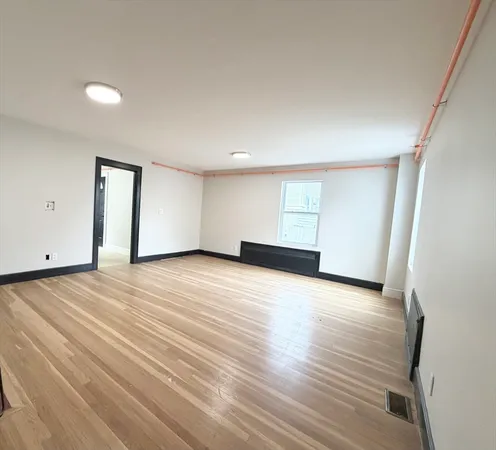 a view of an empty room with wooden floor and closet