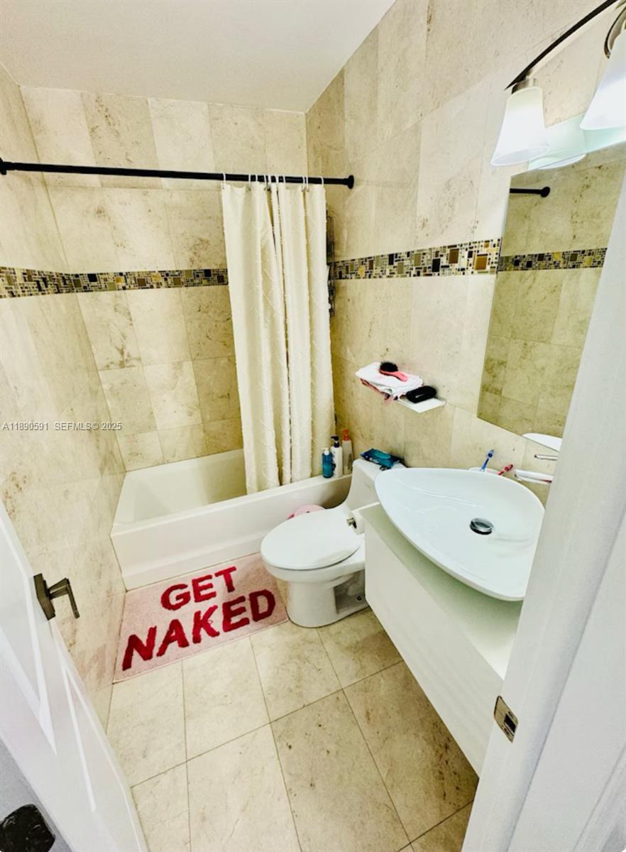 9240 Byron Avenue Surfside, FL 33154 - Photo 25 of 27 a bathroom with a sink and a shower curtain