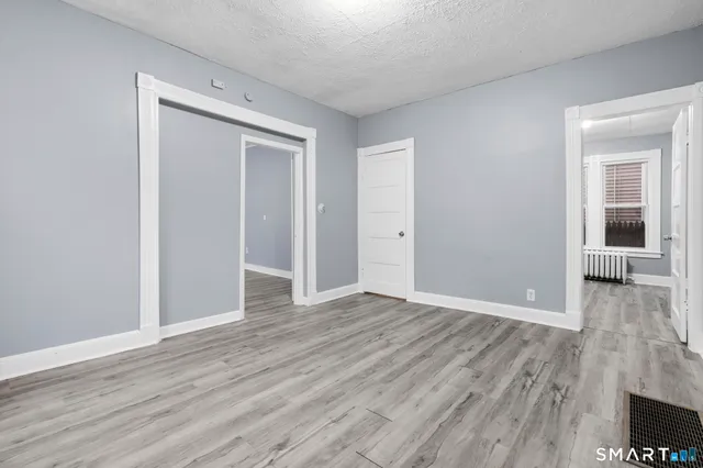 a view of an empty room with wooden floor and a window