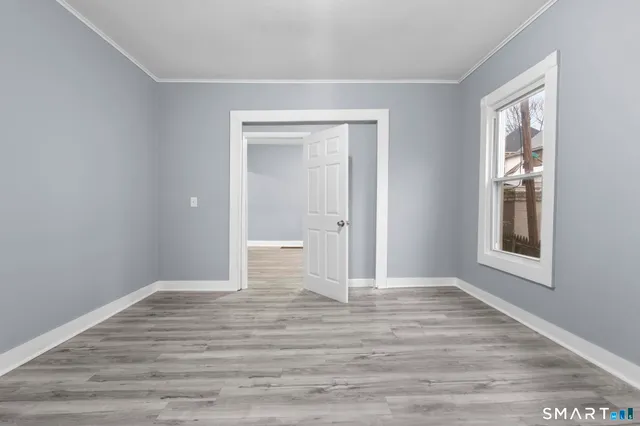a view of an empty room with window and wooden floor