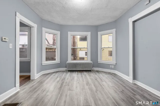 an empty room with wooden floor and windows