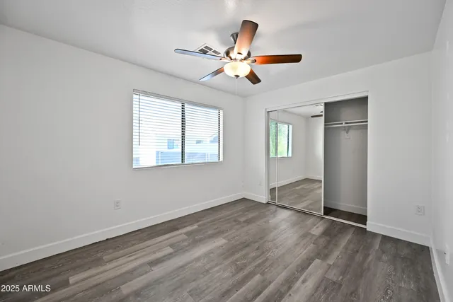 a view of empty room with wooden floor and fan