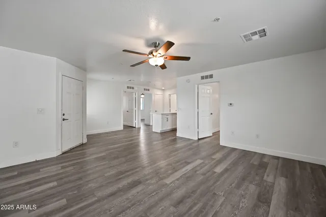 a view of an empty room with a window and wooden floor