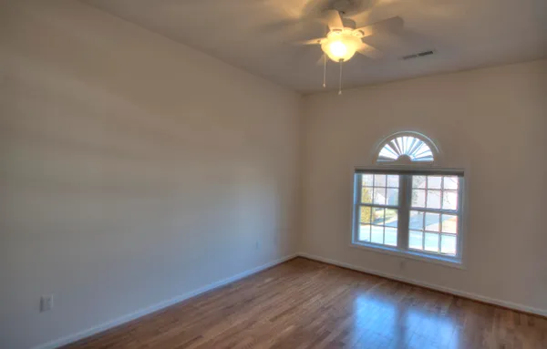 a view of an empty room with wooden floor and a chandelier