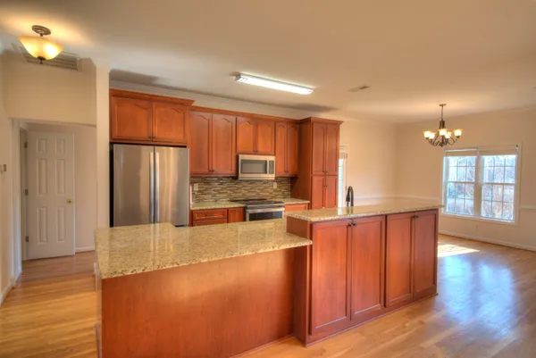a large kitchen with stainless steel appliances wooden floors and large cabinets